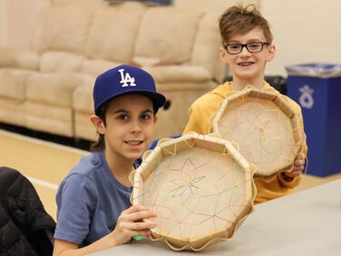 Two grade 5 students holding up the drums they made